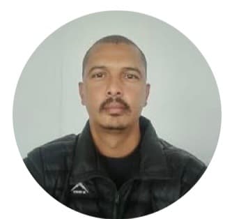 Circular headshot of a man with a mustache wearing a black puffer jacket against gray.